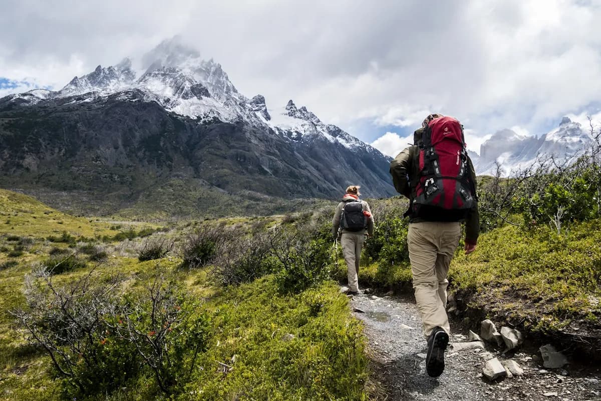 Randonneurs sur un sentier des Pyrénées entre verdure et sommets enneigés